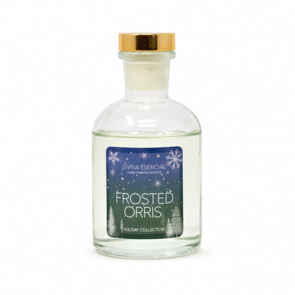 A clear glass bottle of Livna Essential handcrafted scents 'Frosted Orris' with a gold cap and a blue winter-themed label, set against a plain white background.