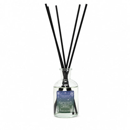 A reed diffuser bottle with a clear glass container, black reeds, and a frosted orange scent label, shown on a plain white background.