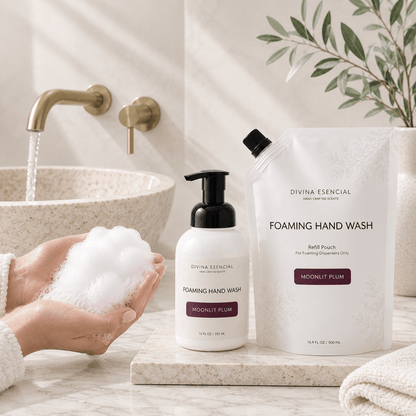 Divina Essential Foaming Hand Wash set in a bright bathroom setting, featuring a white pump bottle with a black pump and a matching refill pouch on a marble tray next to a sink with running water and a hand holding foam.