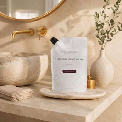 Foaming hand wash bottle on a marble countertop with a decorative mirror and plant in the background.